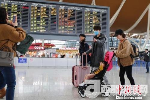 旅客帶著孩子前往辦票柜臺辦理登機手續(xù)?！∫罅⑶?攝