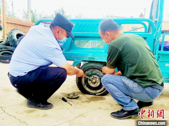 賽旦與民警共同維修三輪摩托車。　依力哈木江 攝