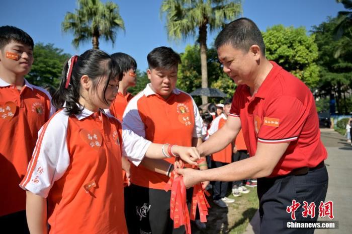 資料圖：廣西華僑實(shí)驗(yàn)高中的教師為高三學(xué)子系上紅絲帶，盼望學(xué)子高考必勝。 俞靖 攝